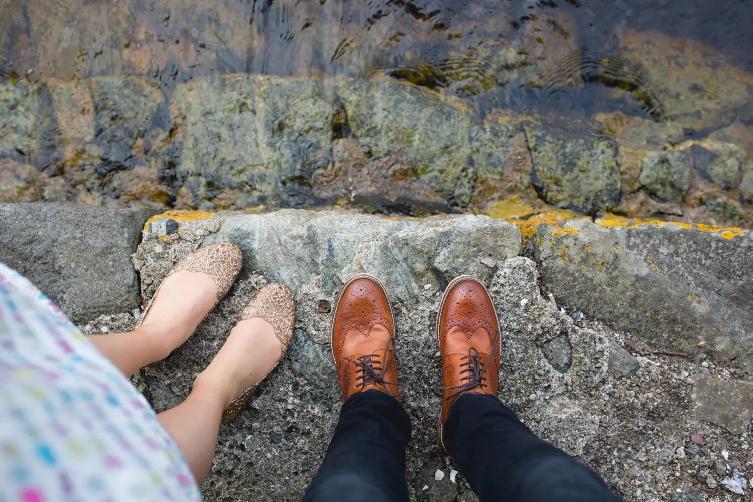 Brown wingtip shoes with brogueing paired with raw denim jeans