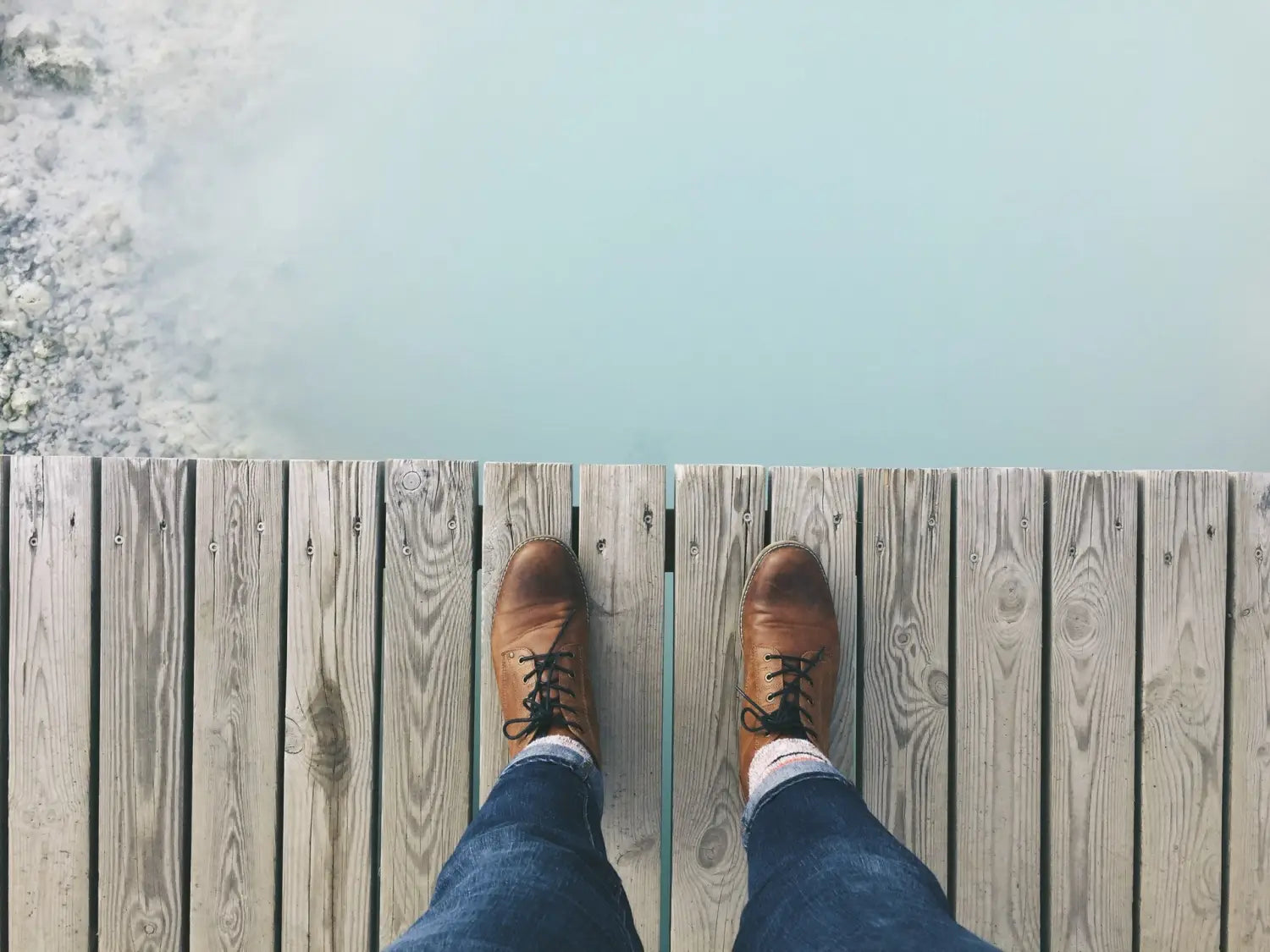 A view from above of blue jeans and brown dress shoes