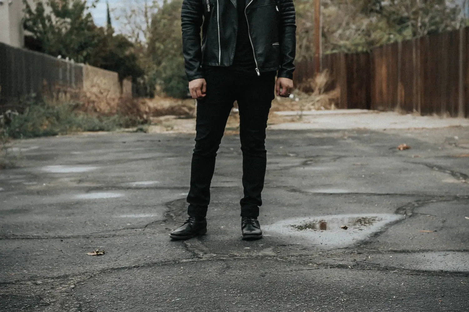 A man wearing black leather boots with a matching black leather jacket