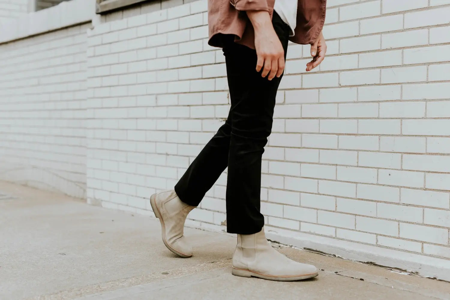 A man wearing black cuffed jeans and white Chelsea boots