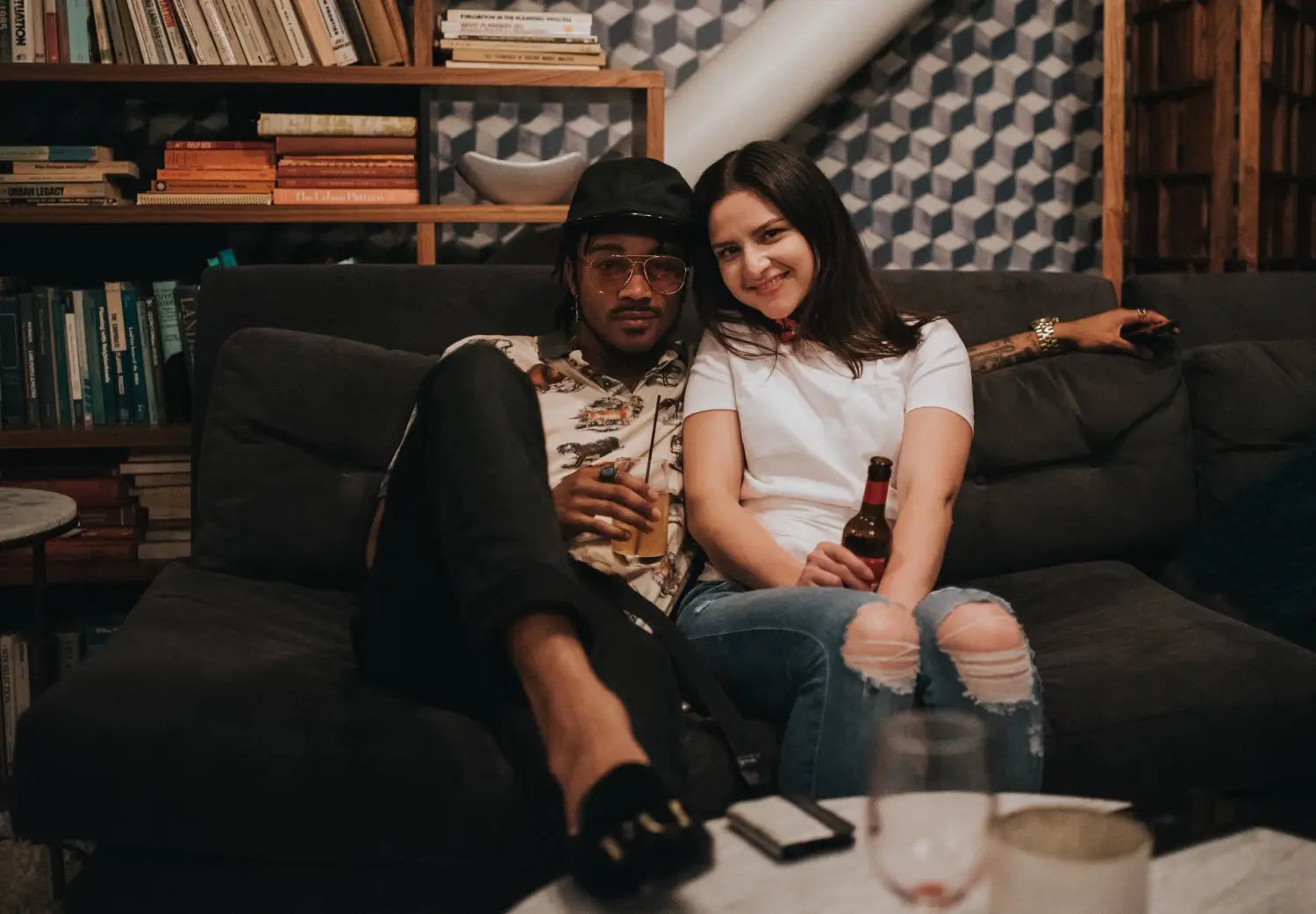 A man wearing smoking slippers sitting on a couch next to a woman